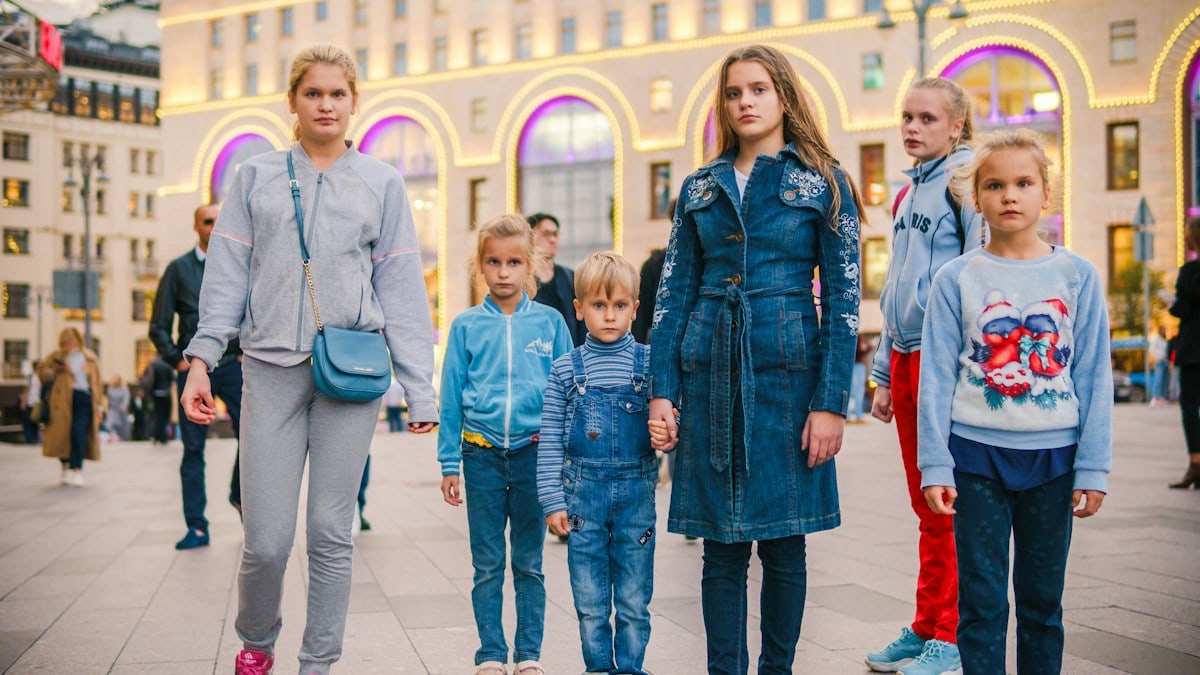 a group of children stands in the crowd on the street